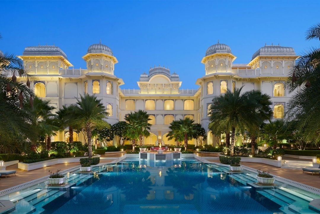 The Leela Palace Jaipur illuminated at dusk with its central pool and gardens