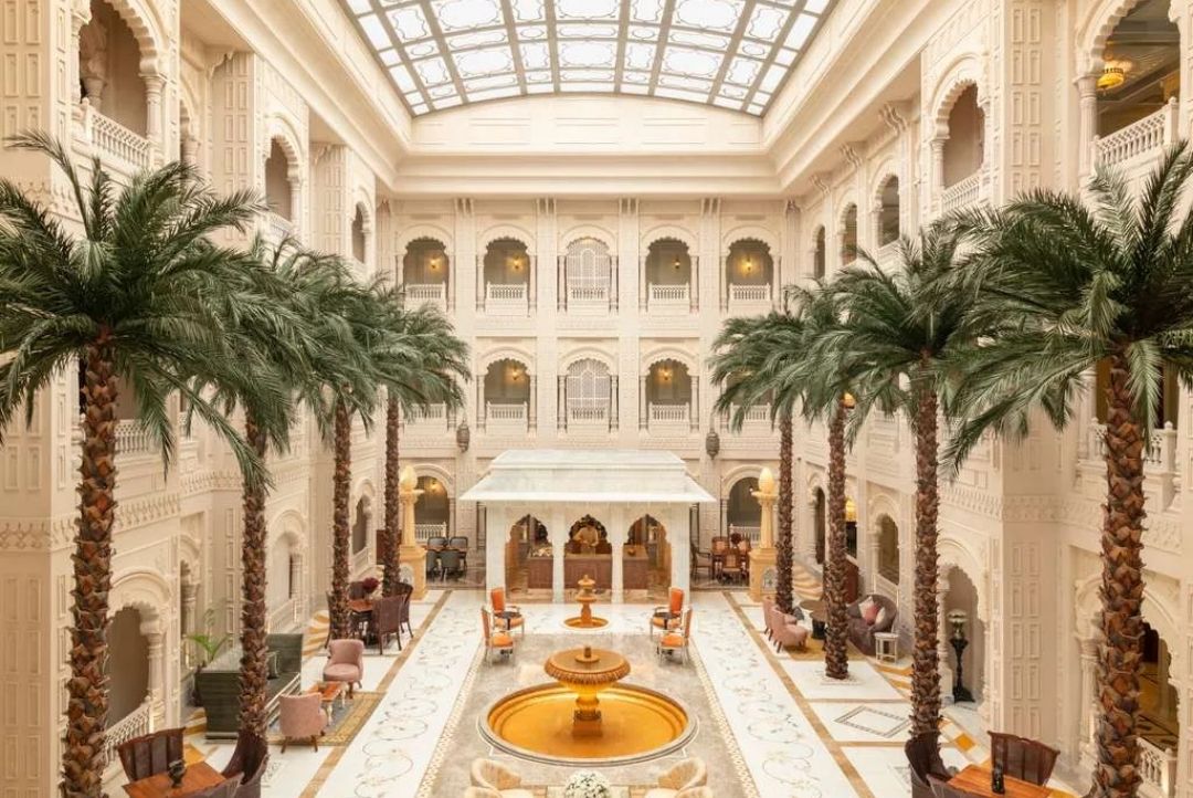 Grand skylit atrium lobby with palms at Raffles Jaipur