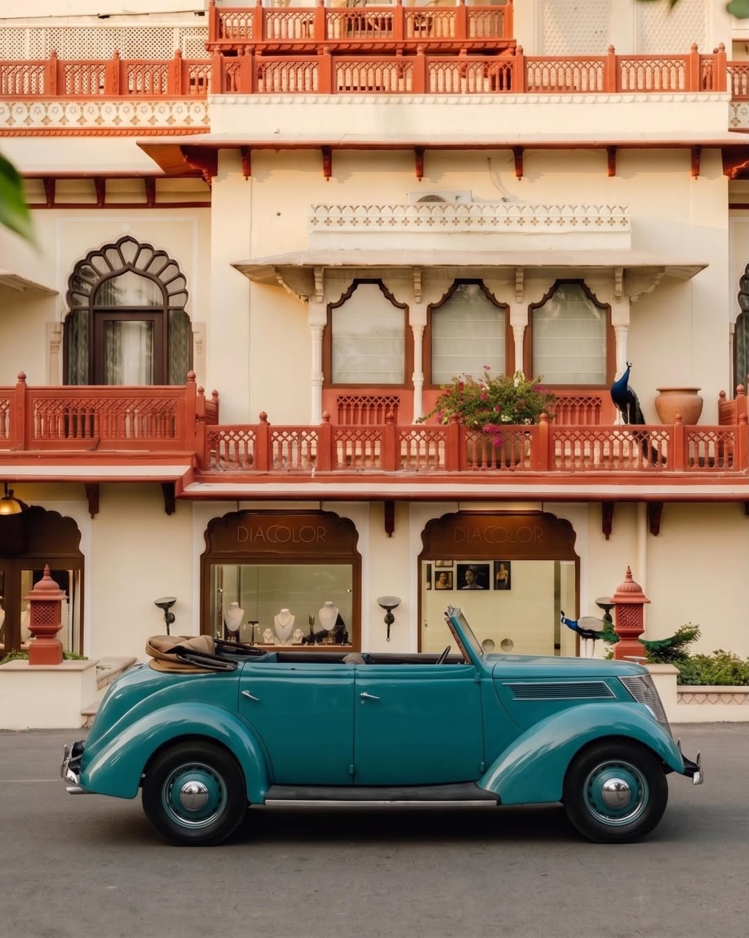 Rambagh Palace facade with a vintage car and resident peacock