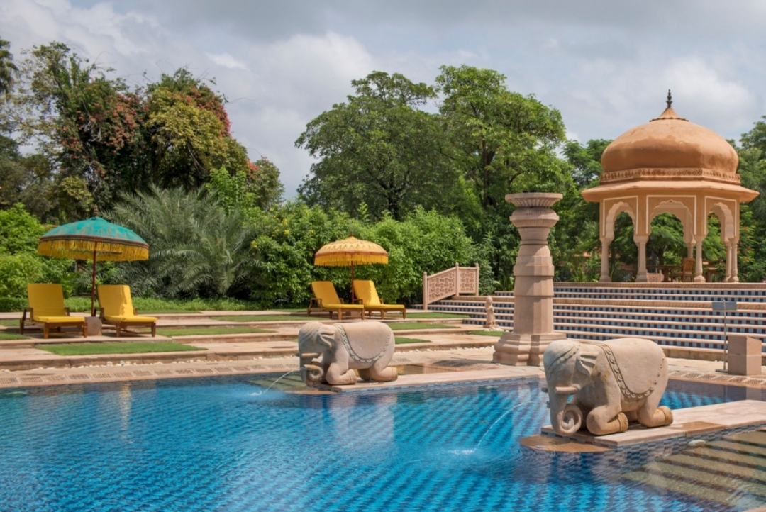 The Oberoi Rajvilas, Jaipur — swimming pool with elephant fountains and domed chhatri
