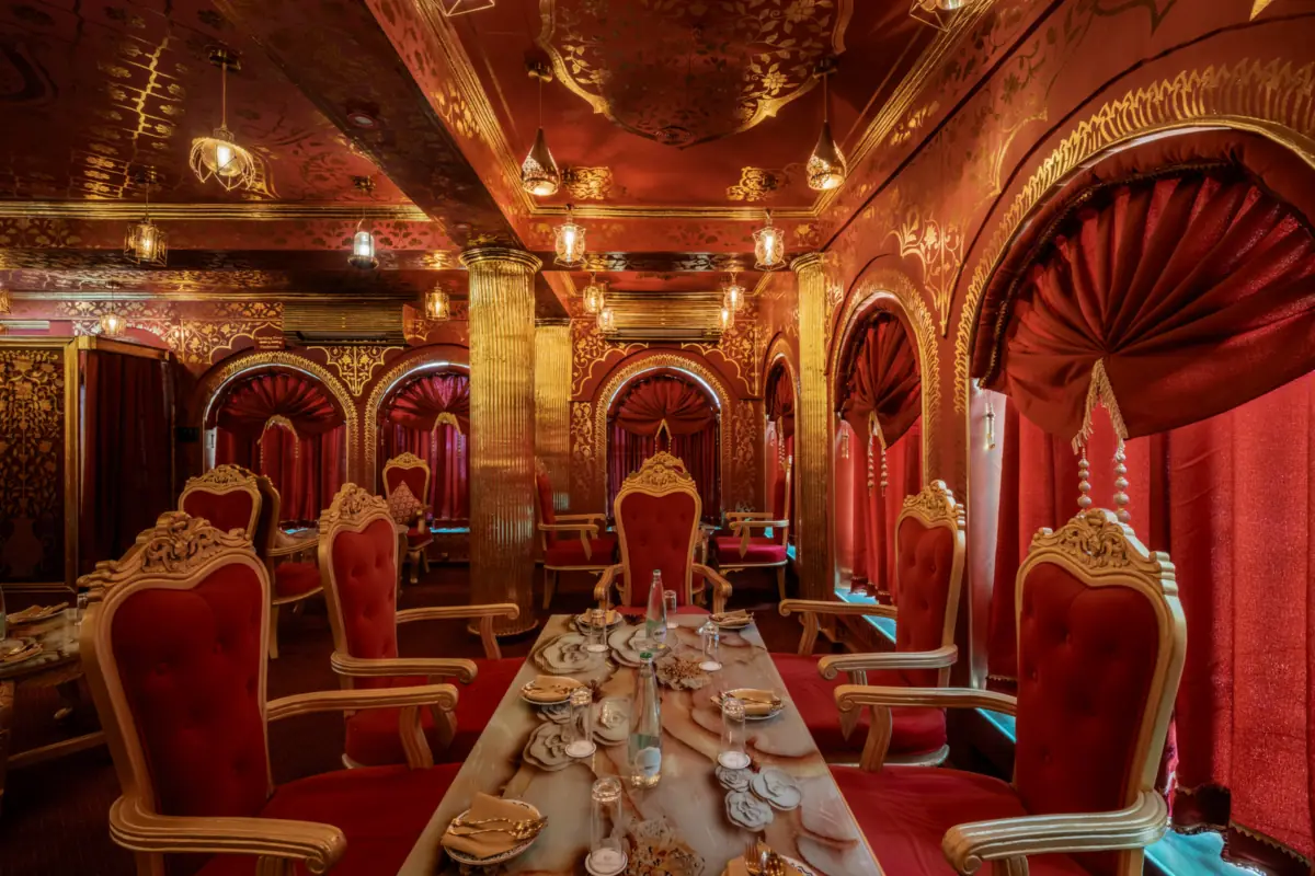 A table set for dinner in the red-and-gold dining hall of Kurki Palace, Jaipur