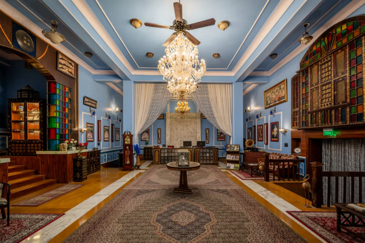 The blue lobby of Kurki Palace in Jaipur, with a crystal chandelier, stained-glass windows and framed portraits