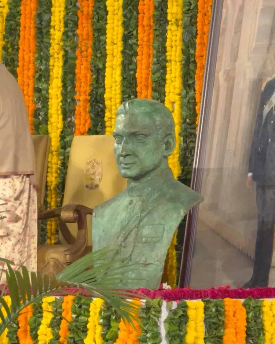 A bust surrounded by orange and yellow marigold garlands on the stage